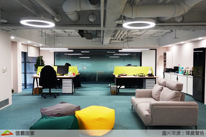 總公司希望每一位員工在工作中也可以保持安全社交距離，所以辦公桌選擇用較大的尺寸，利用跳色的隔板保留基本私人空間，黑色牆面搭配使人心情沉靜的藍色系防焰地毯讓辦公室呈現出沉穩柔和的氛圍；後方的大會議室一樣使用小會議室玻璃中段霧面的處理方式，讓會議進程不受外部干擾。