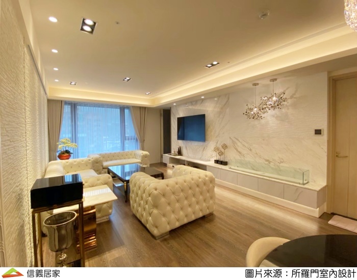 電視牆面與下方櫃體檯面採用同塊石材設計，與電視櫃相近的紋路色系互相映襯，巧妙放大主牆面延伸視覺效果，由木質地板與坎燈透出的射線，柔和客廳氛圍，透露出屋主典雅細緻又大方的品味。
