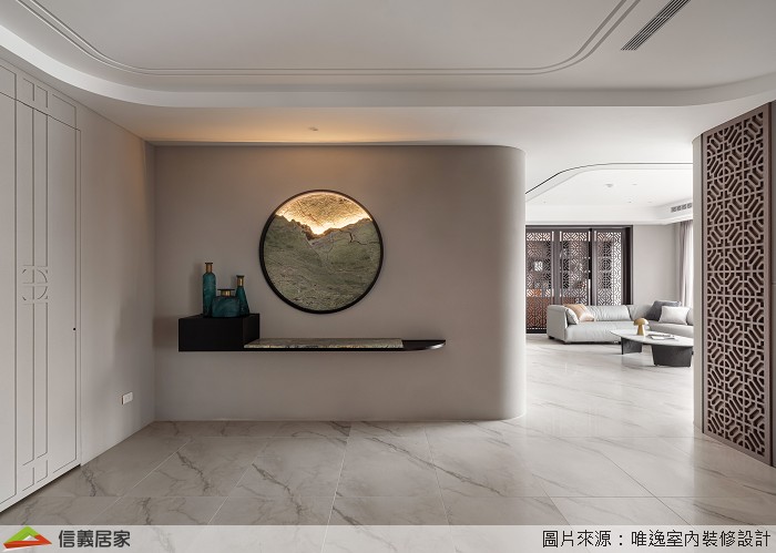 玄關牆面設計一面圓形窗景,透過光影的映照,在空間中重新架構組織輪廓,另一側設置隱藏收納櫃,讓居家收納隱形顯得美觀不繁雜。玄關主牆轉角處的圓弧形水墨風華,便是概念意化後落實的呼應,並展延至中島區域。